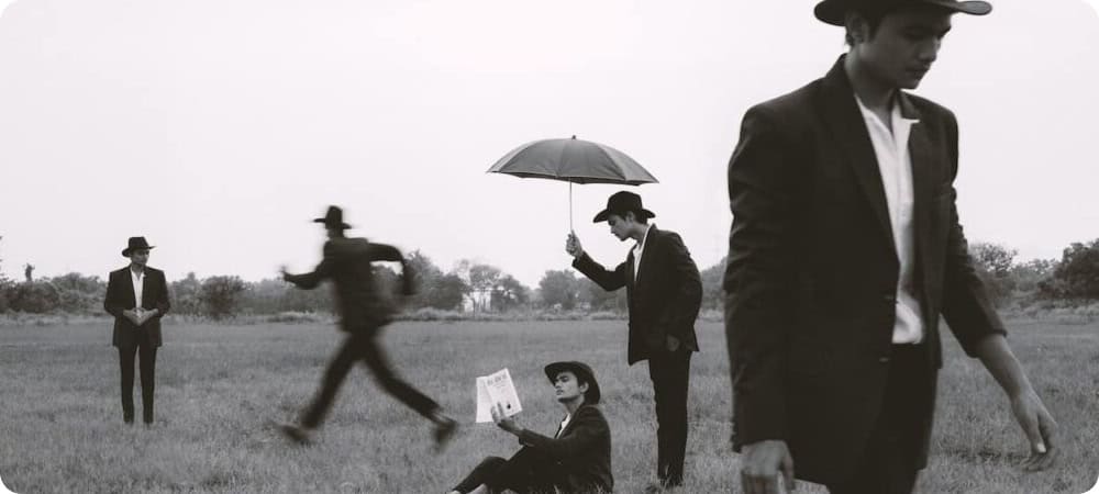 This photo shows a business person appearing several times on a grass landscape. He is wearing a suit and a hat, sometimes appearing with an umbrella, paper or running. This photo depicts the typical mortgage broker chasing after clients to get the information needed to work out the best finance options for the client.