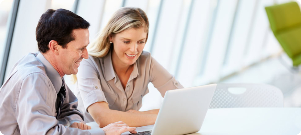 A lady and a man are sitting at a table with a laptop in front of them. They appear to be talking about important and exciting business plans. Perhaps they have time to do this as they use a Client Collaboration Software.