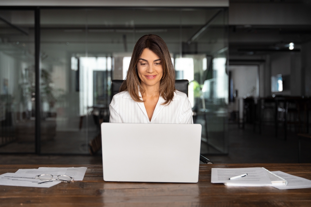 This image shows bookkeeper Kylie, sitting smiling in front of an open laptop